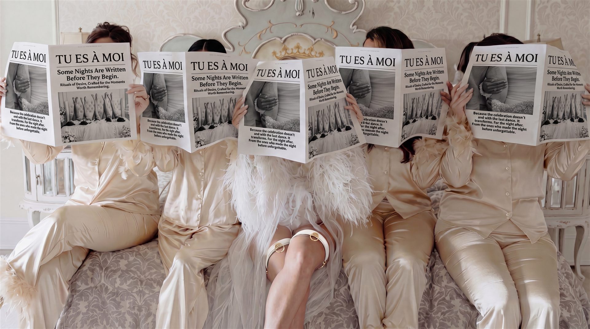 Bride surrounded by bridesmaids in white satin robes, celebrating together in a luxury bridal suite