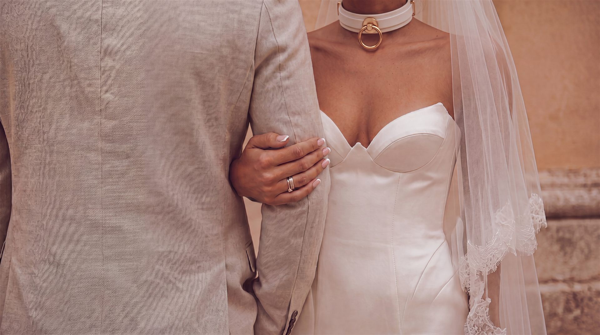 Bride and groom's hands entwined — lace wedding dress, matching rings, a quiet intimate moment